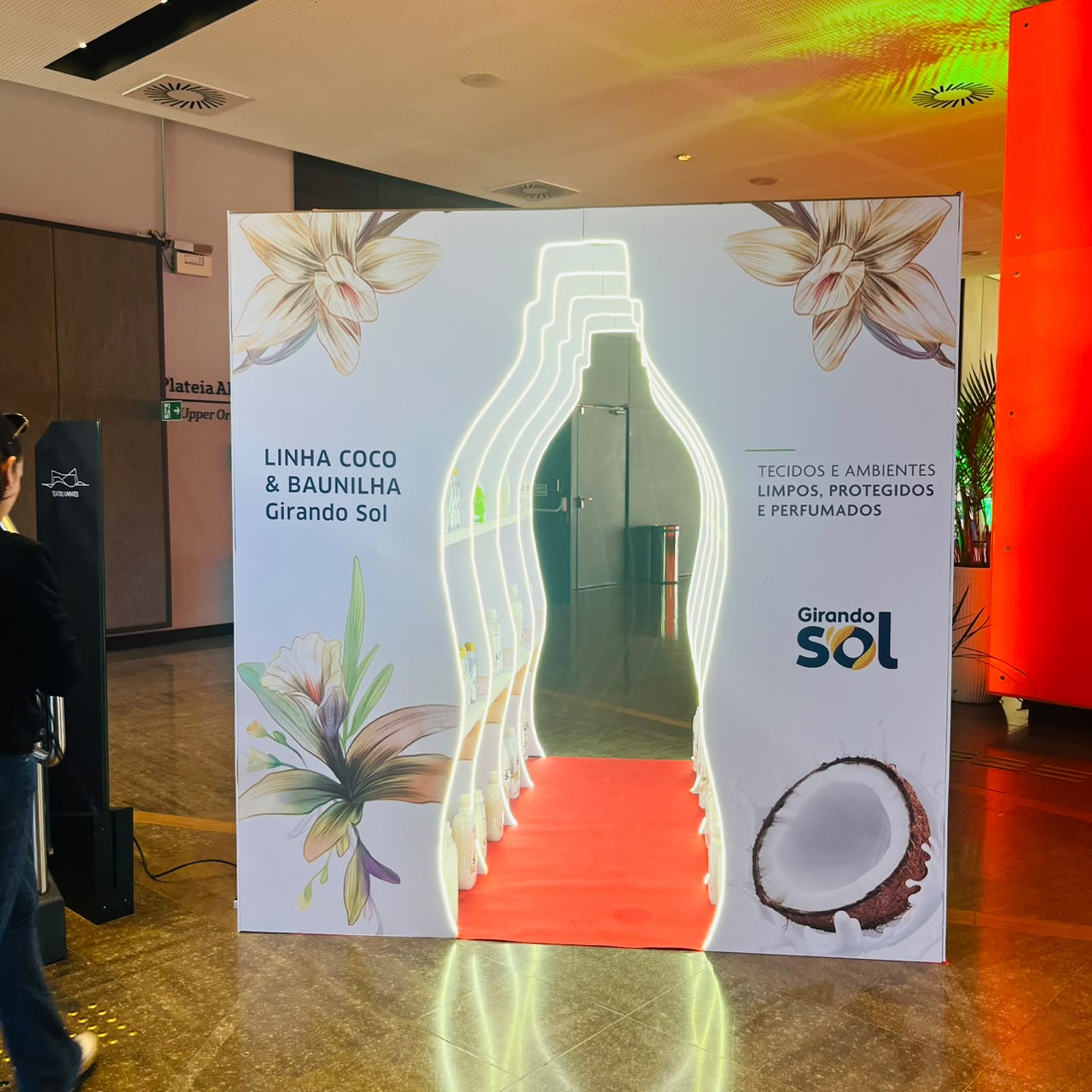 Portal com contorno iluminado em formato de frasco para a linha Coco e Baunilha da Girando Sol